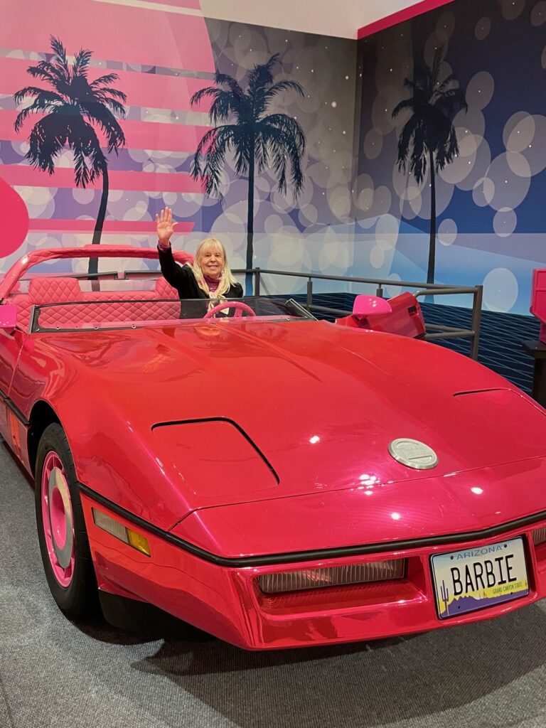 TWE's Pam Burke sitting in life-size Barbie ultra 'vette' at Phoenix Art Museum's Barbie: A Cultural Icon Exhibition/Photo: Courtesy P. Burke